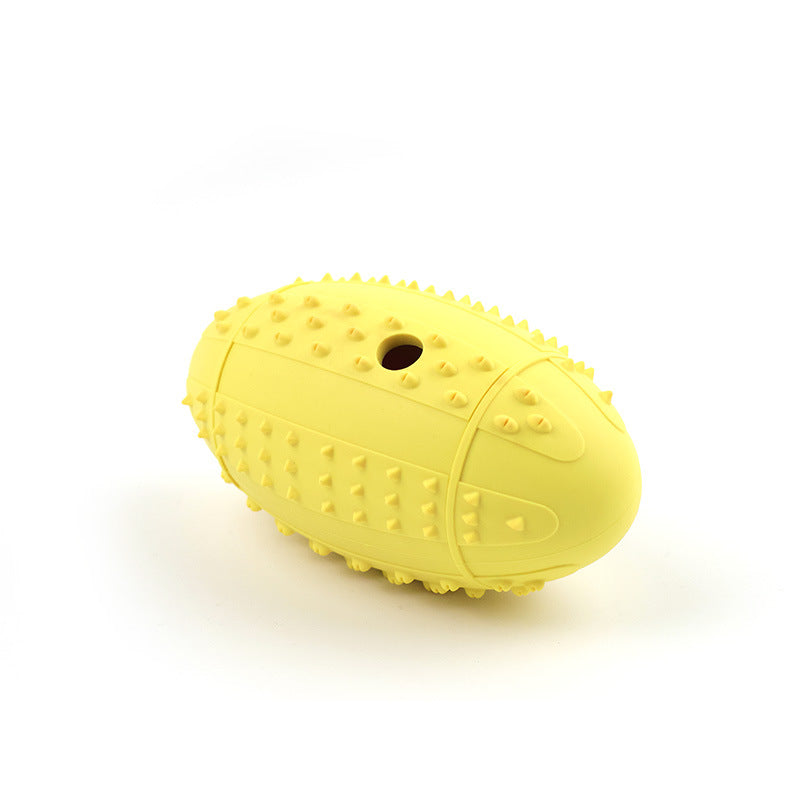 Yellow rubber rugby ball dog toy showing the raised nubs and the moulded seam round the middle