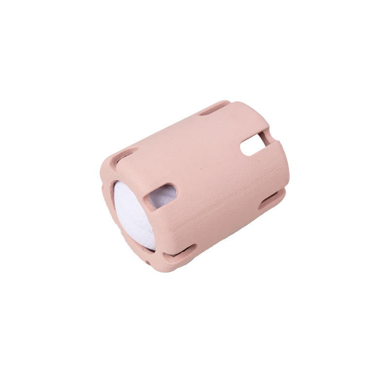 Pink slotted rubber dog ball cage holding a white textured ball