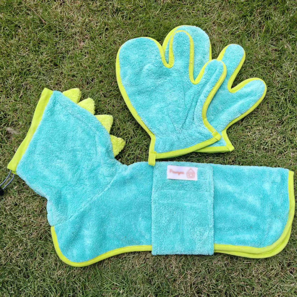 Teal dinosaur dog bathrobe with lime binding and spined hood, laid out with drying mitts