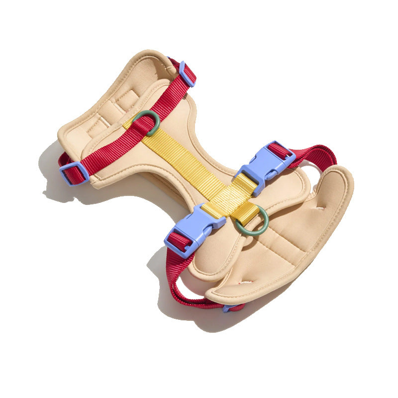 Padded tan dog harness with red and yellow webbing, blue side-release buckles, green rings