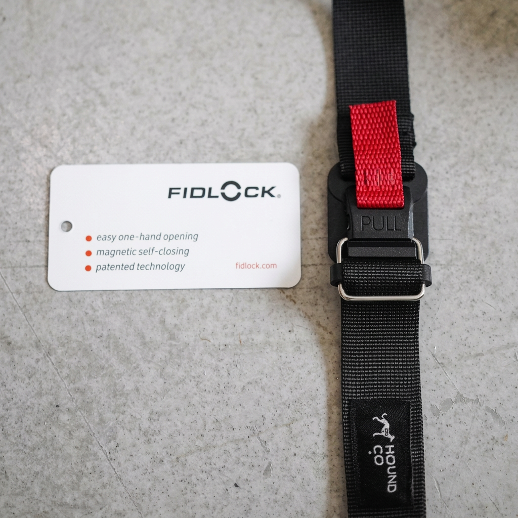 Close-up of the Quickwear black strap, red pull tab and FIDLOCK buckle beside its product information card.