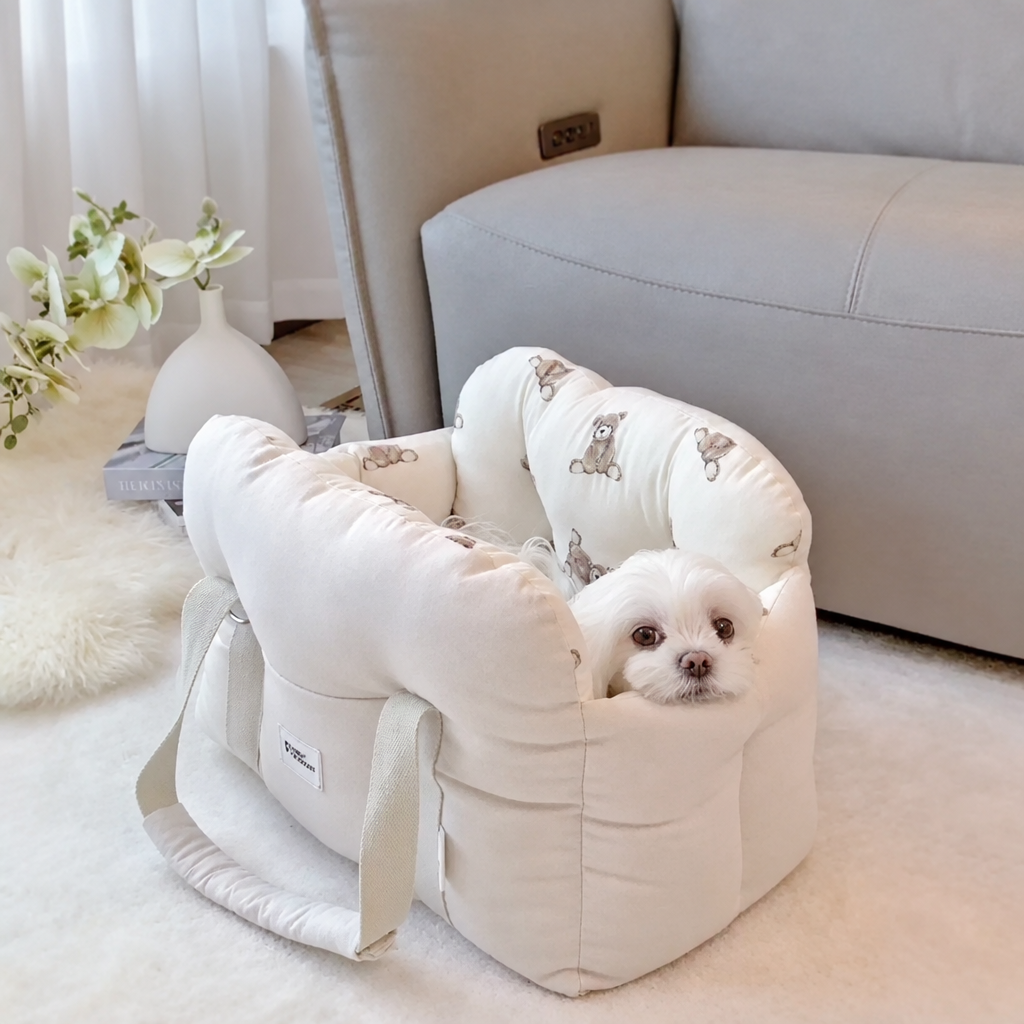 Small white dog in a beige carrier with bear-print lining