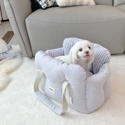 Small white dog in a grey carrier with grey gingham lining