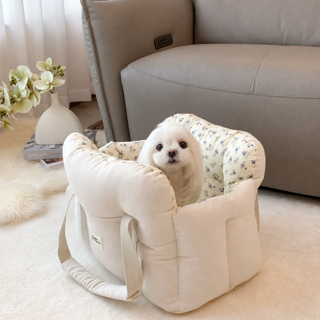 Small white dog in a cream carrier with blue floral lining