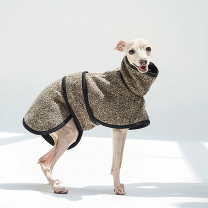 Side view of a white dog in the brown-taupe Metropolitan coat with textured fabric, high collar, black binding and wraparound body coverage.